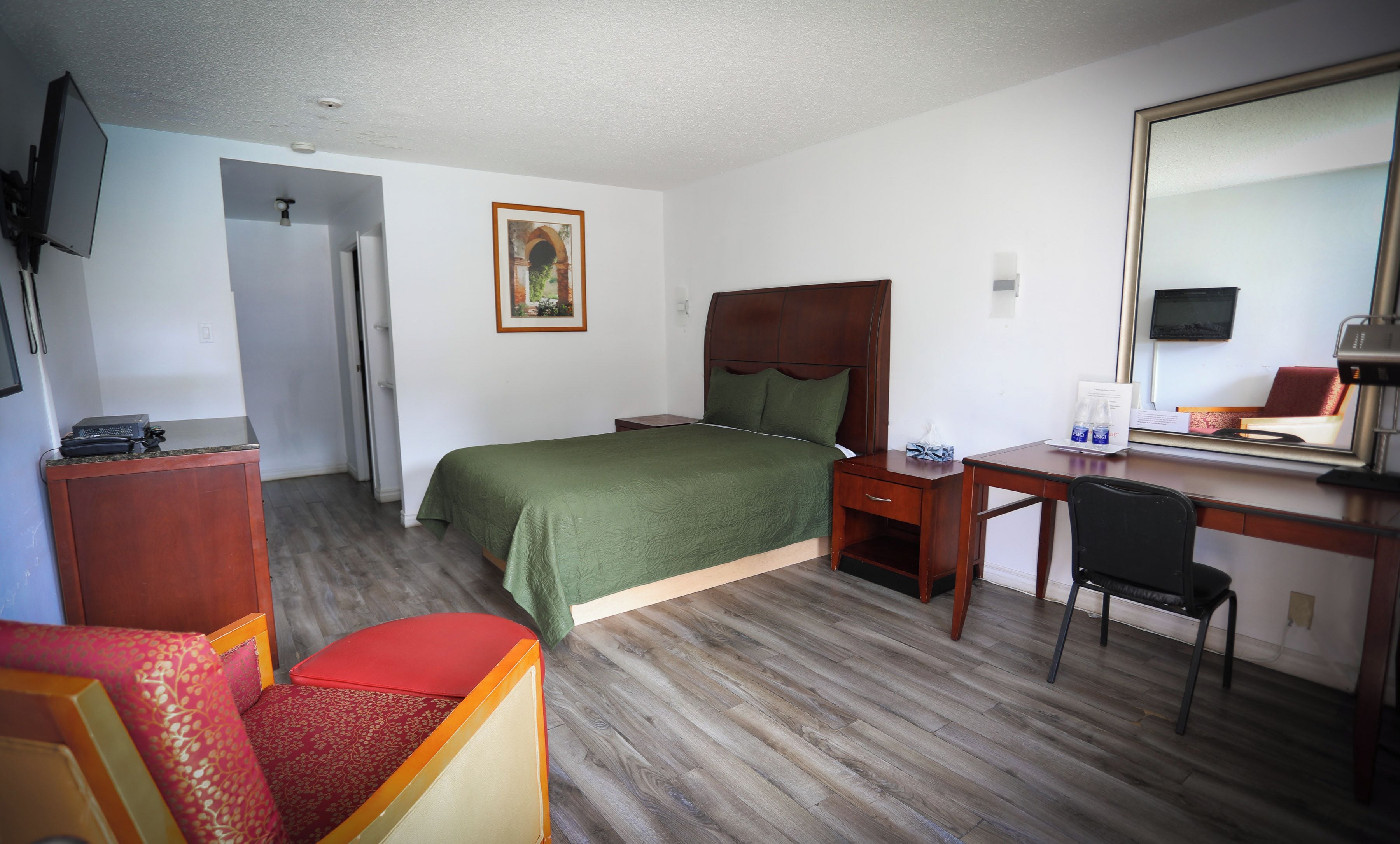Una habitación de hotel con cama, escritorio, silla y televisor.