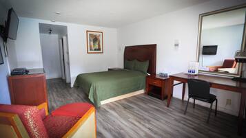 Una habitación de hotel con cama, escritorio, silla y televisor.