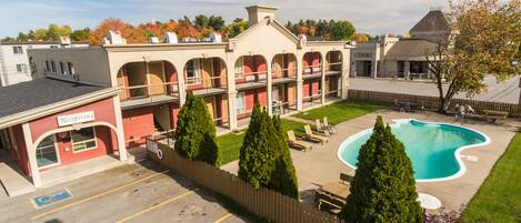 Un hotel con piscina, mobiliario de exterior y una zona de recepción.