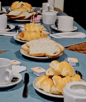 Une table dressée avec du pain, des croissants et de petits pots de beurre, probablement dans un coin repas.