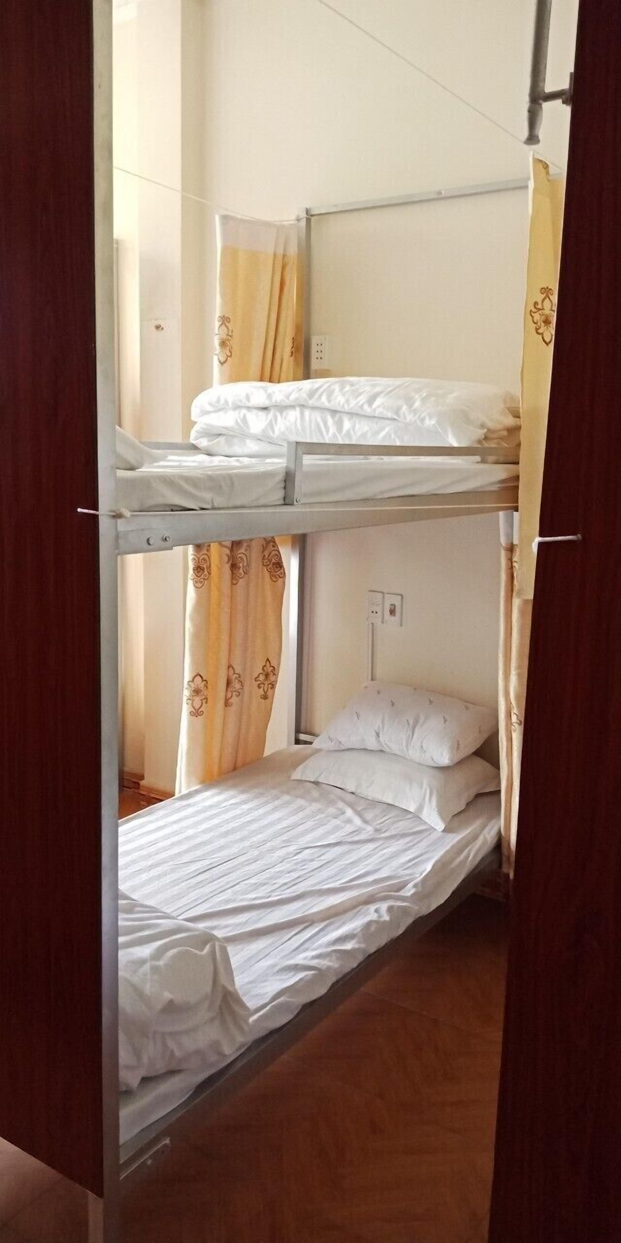 A bunk bed room with a curtain and a single bed.
