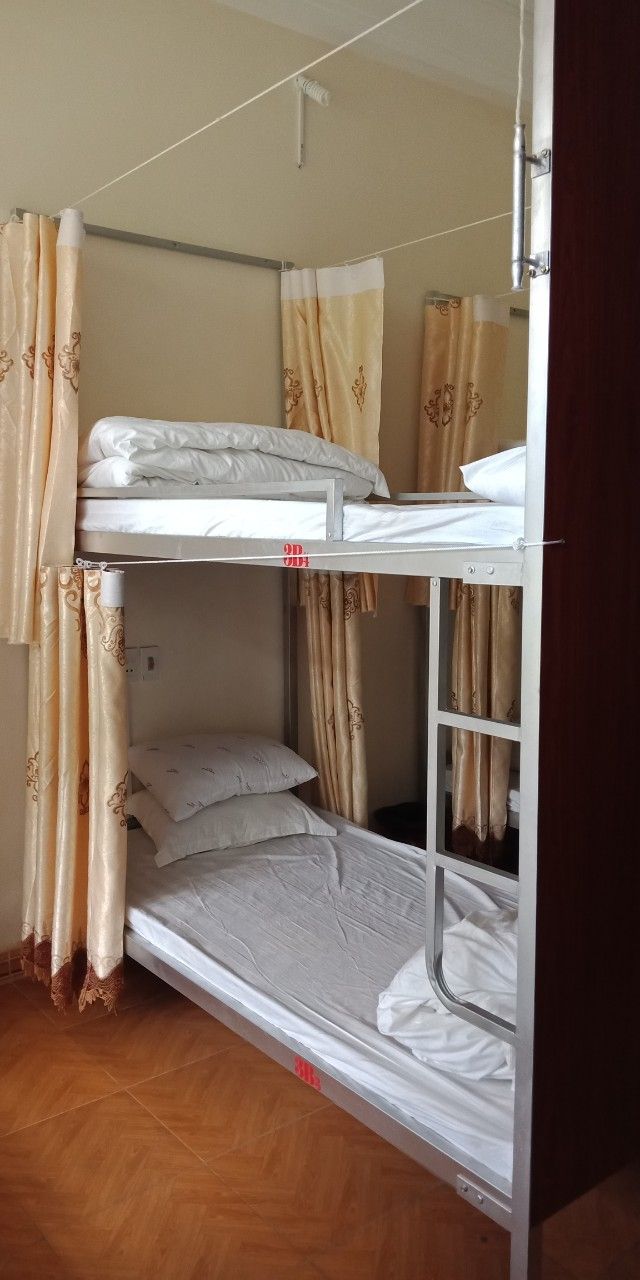 A bunk bed room with curtains and a wooden floor.