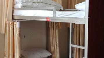 A bunk bed room with curtains and a wooden floor.