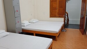 A room with two single beds, a wooden wardrobe, and a small table.