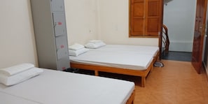 A room with two single beds, a wooden wardrobe, and a small table.