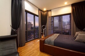 A modern bedroom with a large bed, a chair, and a view of the cityscape through large windows. - 4R3B The Elements Ampang Lux Condo Hosted By TJ's Speakeasy (Kampung Berembang)