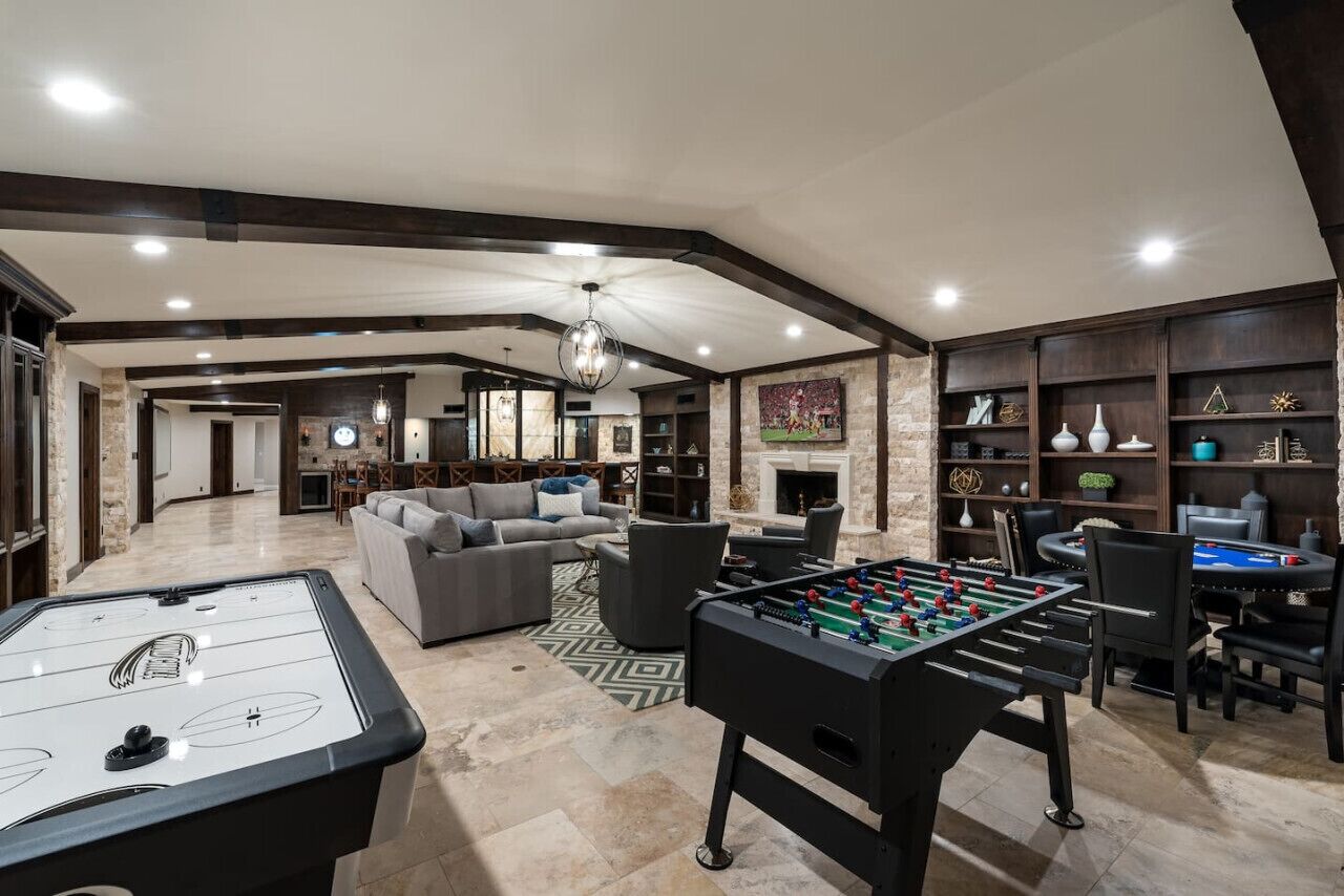 Een ruime woonkamer met een tafelvoetbaltafel, een bank en een open haard.