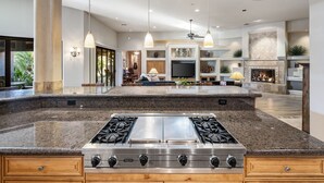 Une cuisine spacieuse dotée d’un îlot central, de plans de travail en granit et d’une cuisinière à gaz Viking en acier inoxydable.