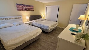 A hotel room with two beds, a desk, a chair, a lamp, a painting, and a door. - Close to beach! Spacious -Condo B (Ocean City)