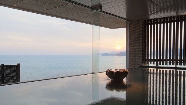 A modern interior with a glass floor leading to a balcony overlooking a body of water. - Yumotokan New Hamajima (Shima)
