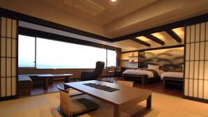 A modern hotel room with a large window, a wooden table, a sofa, and a bed. - Yumotokan New Hamajima (Shima)