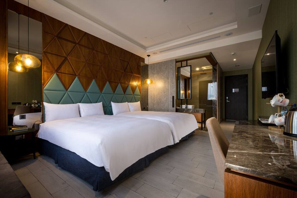 A hotel room with a large bed, a wooden headboard, a marble countertop, and a mirror.