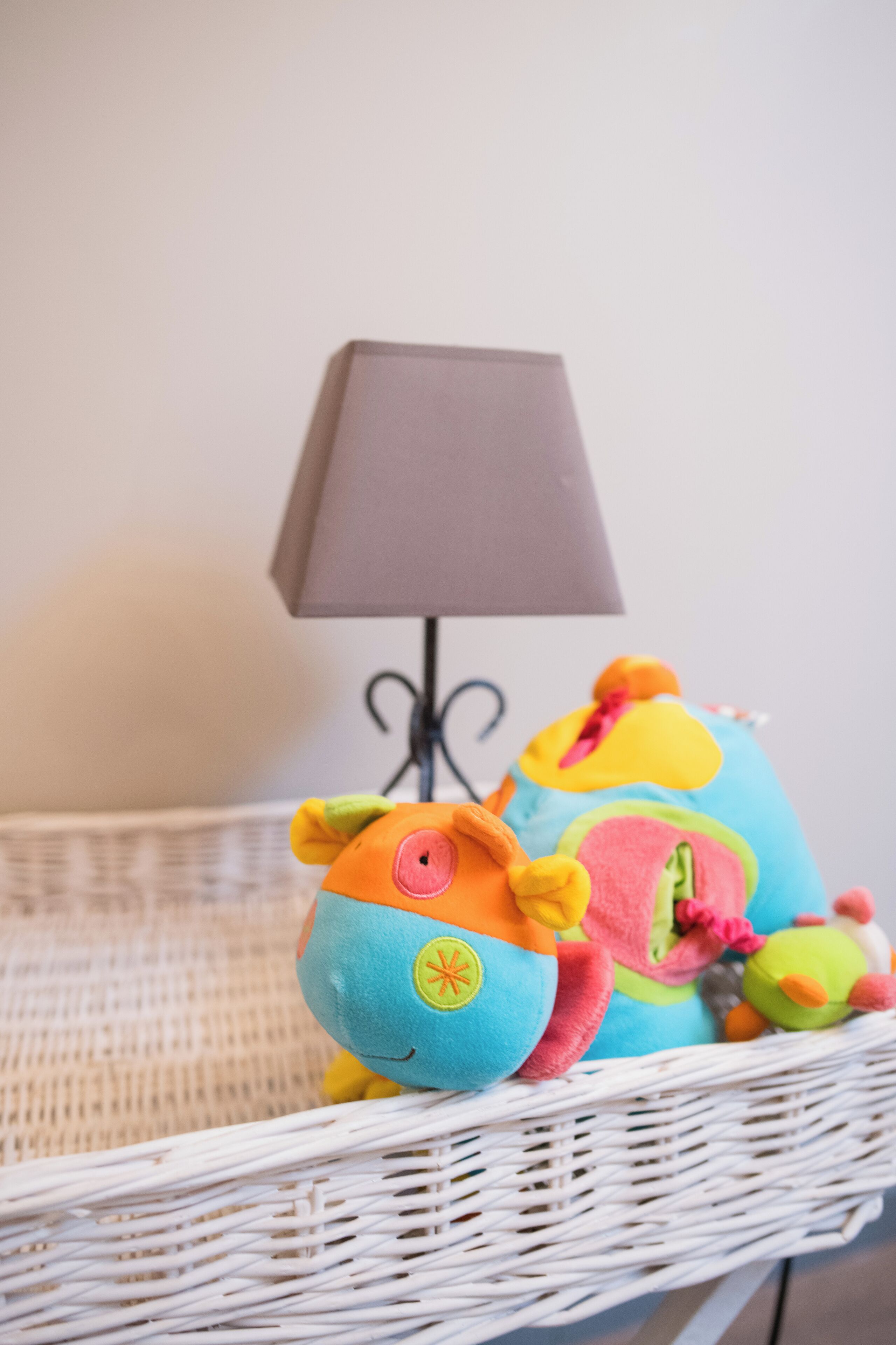 En fletkurv med bløde legetøj og en lampe.