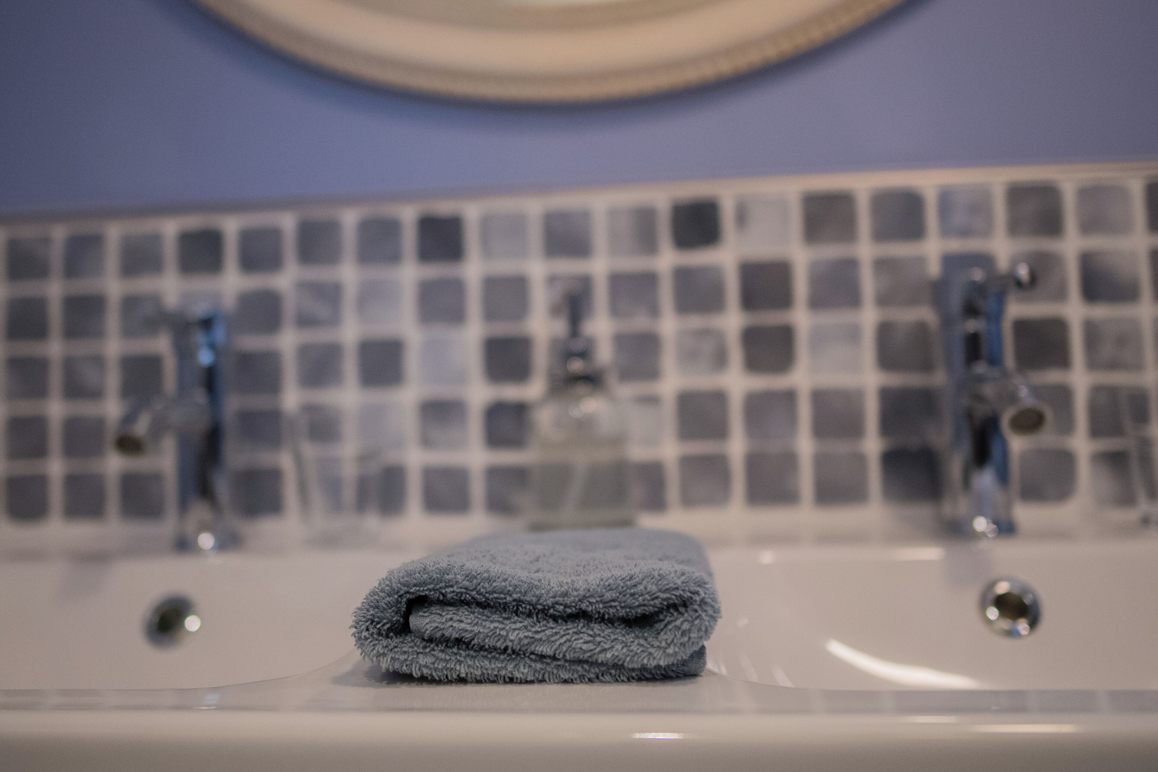 A bathroom with a sink, two faucets, and a tiled backsplash.