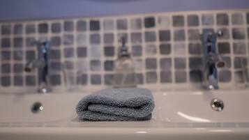 A bathroom with a sink, two faucets, and a tiled backsplash.