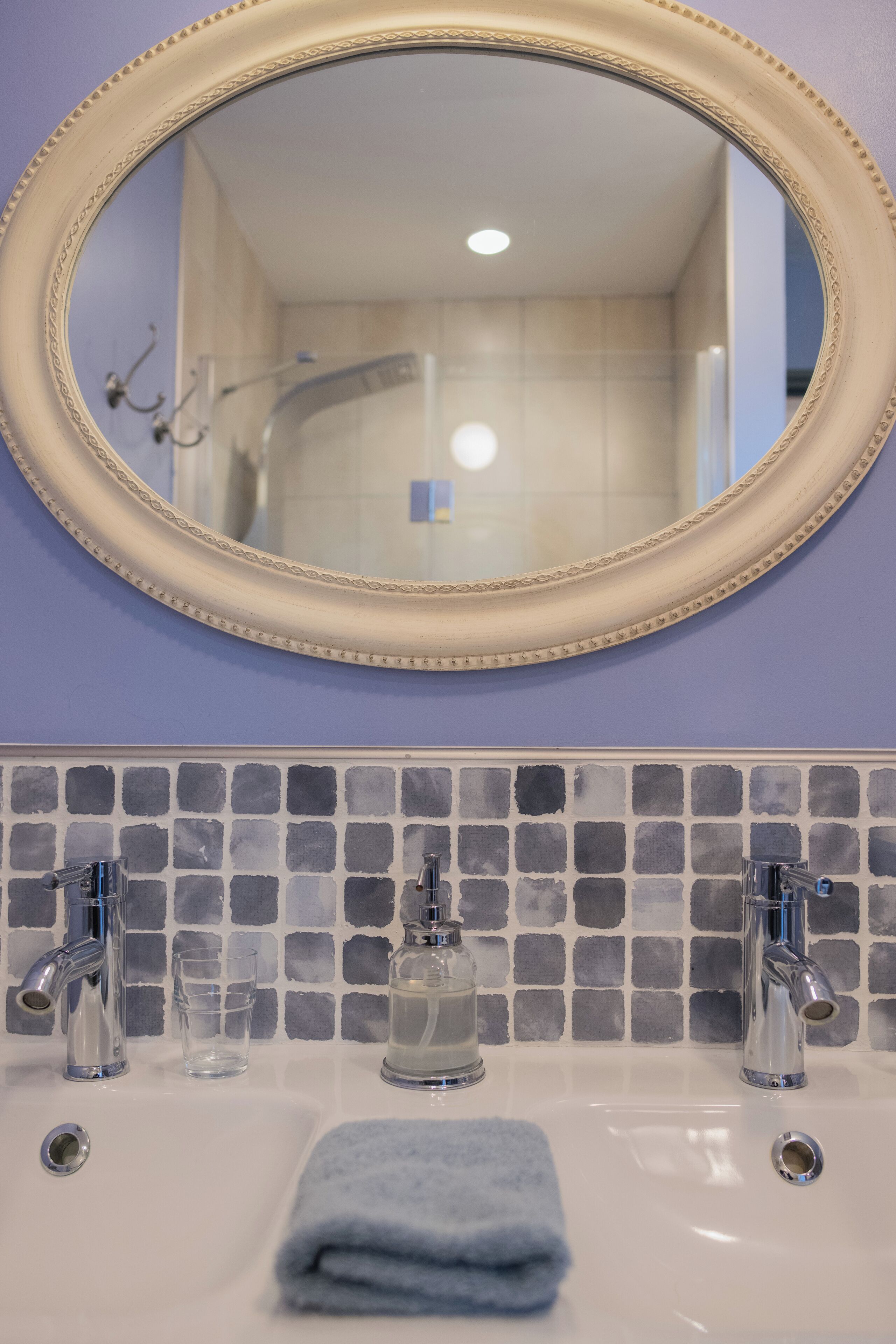 Un baño con espejo, dos lavamanos y salpicadero de azulejos.