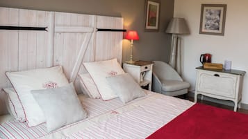 Una cama bien hecha con una colcha a rayas, una manta roja y un cabecero con un detalle horizontal negro.