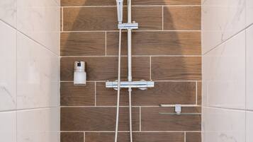 A shower with a wooden wall, a handheld showerhead, and a wall-mounted faucet.