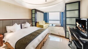 A modern hotel room with a large bed, a desk, a sofa, and a TV. - Haikou Mingguang Shengyi Hotel (Haikou)