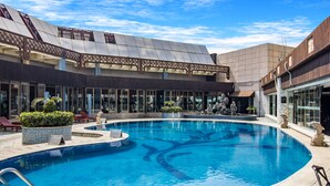 A swimming pool with a modern design, surrounded by lounge chairs and potted plants. - Haikou Mingguang Shengyi Hotel (Haikou)
