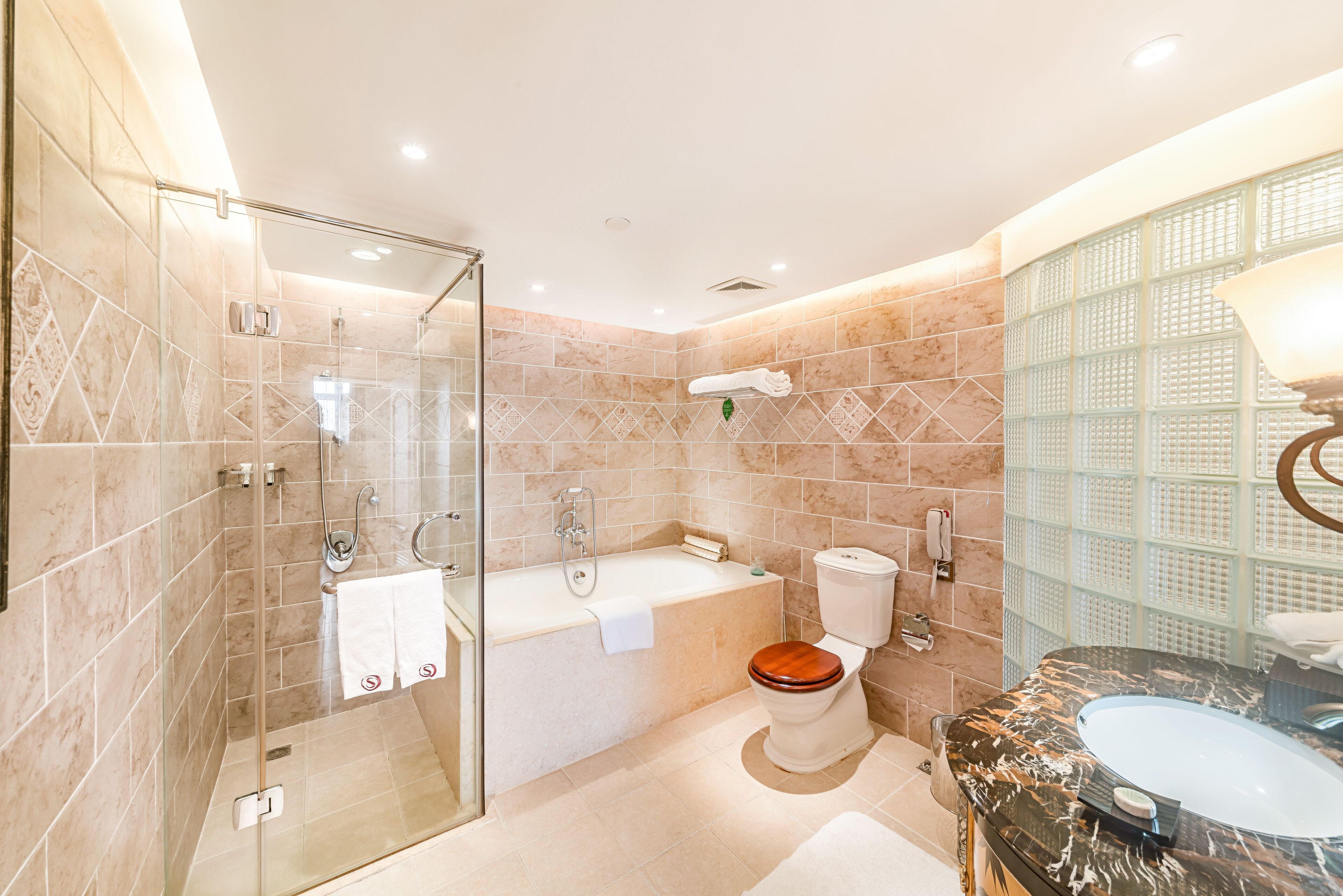 Un baño moderno con ducha de vidrio, bañera independiente y tocador de mármol con lavabo.