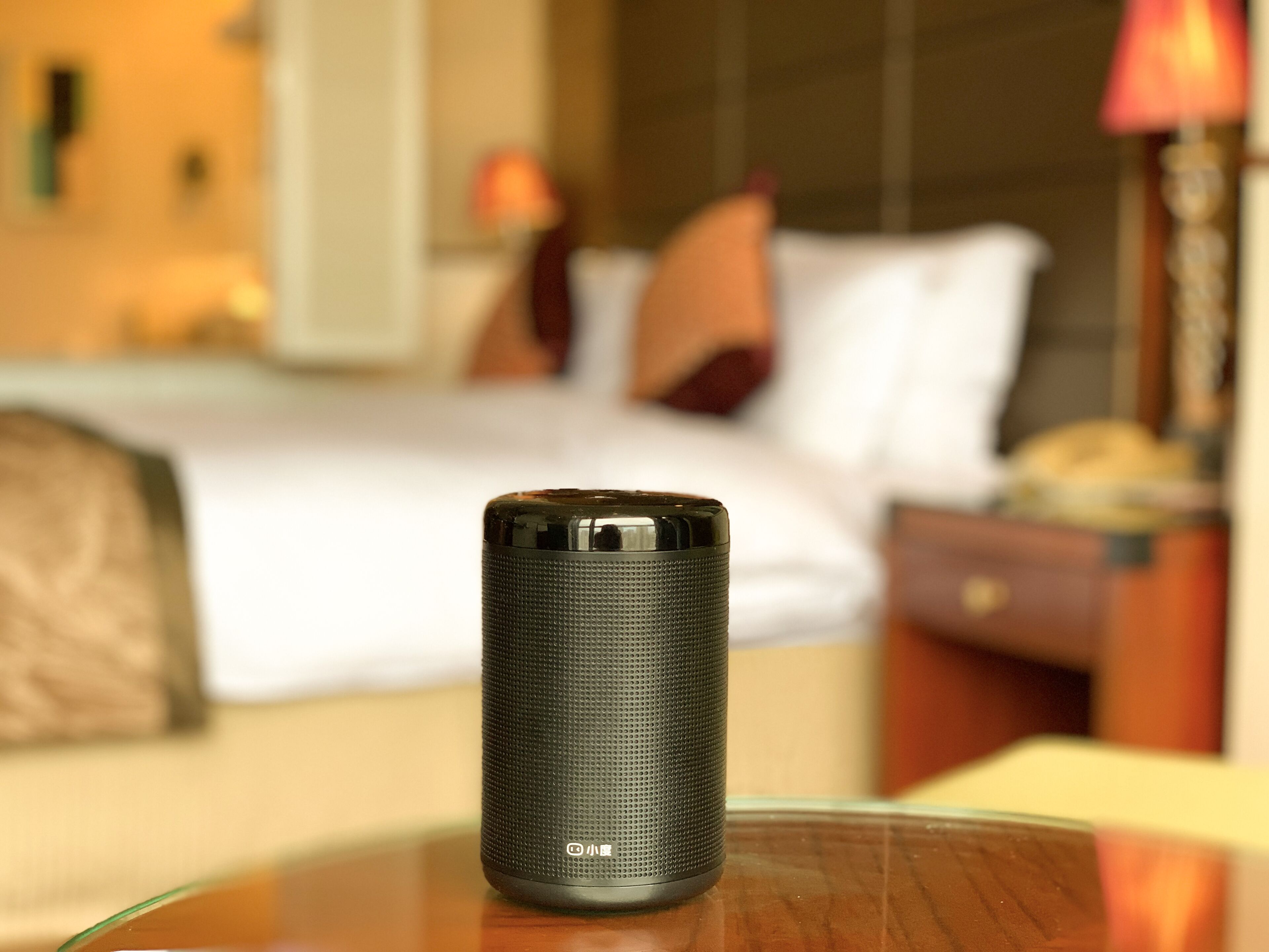 A cylindrical black object on a table in a hotel room.