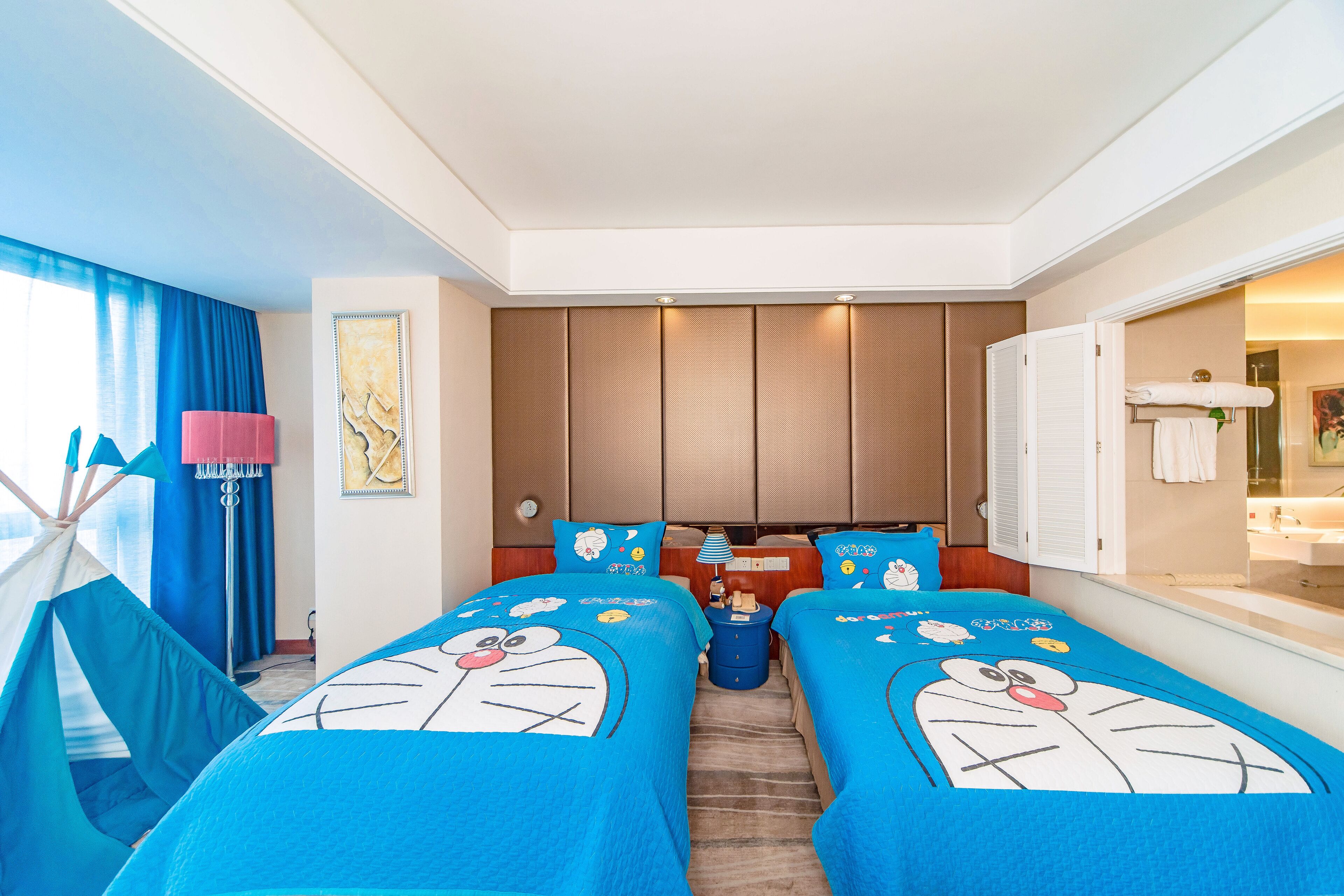 Habitación de hotel con dos camas, una tienda de campaña y un baño visible a través de una puerta abierta.