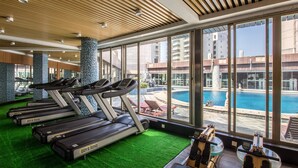 A gym with treadmills and a pool view. - Haikou Mingguang Shengyi Hotel (Haikou)