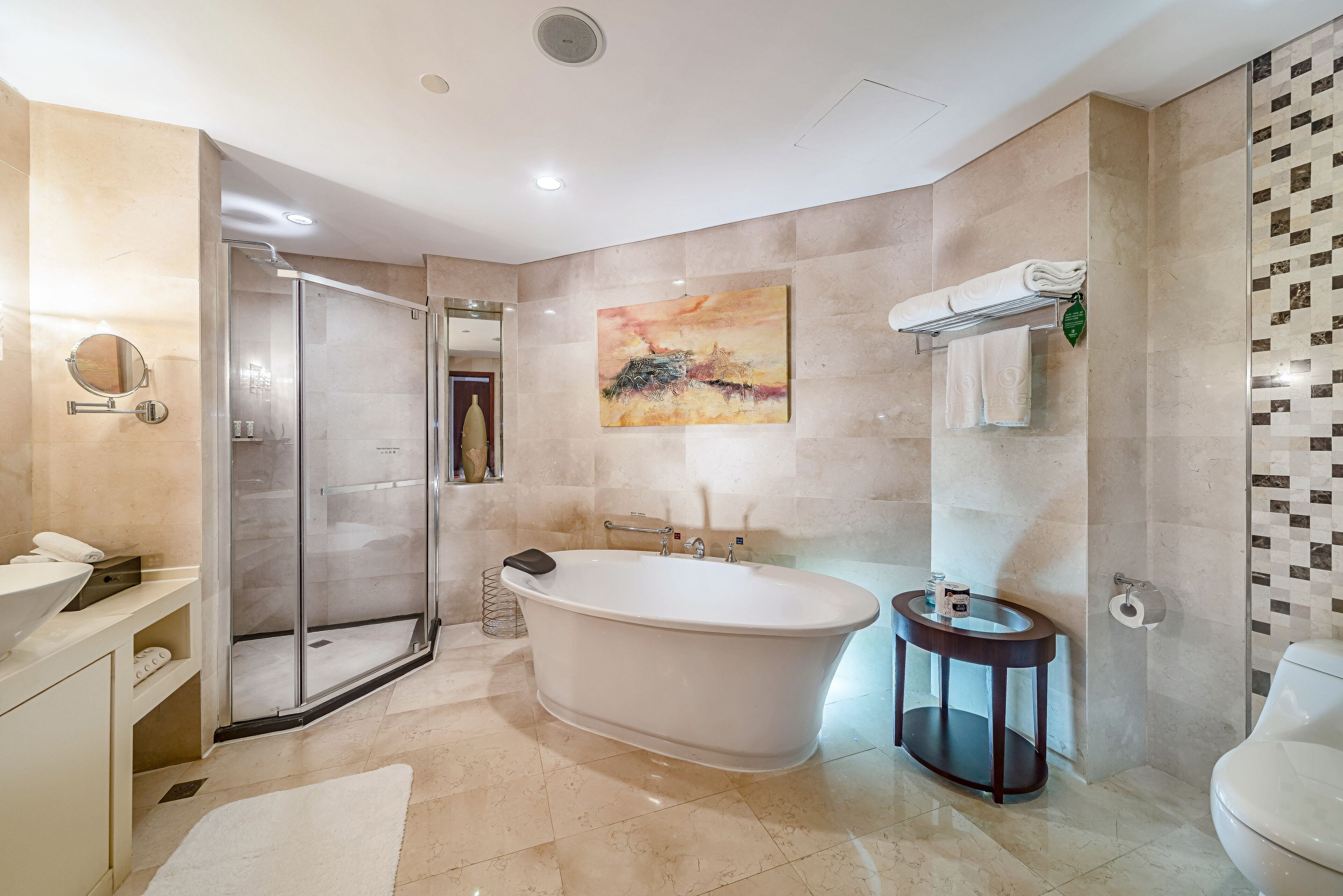 A modern bathroom with a freestanding bathtub, a glass shower enclosure, a round mirror, and a toilet.