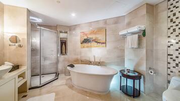 A modern bathroom with a freestanding bathtub, a glass shower enclosure, a round mirror, and a toilet.