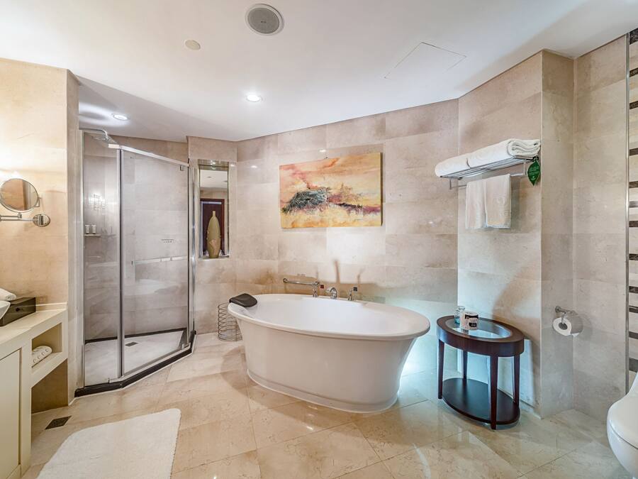 A modern bathroom with a freestanding bathtub, a glass shower enclosure, a round mirror, and a toilet.