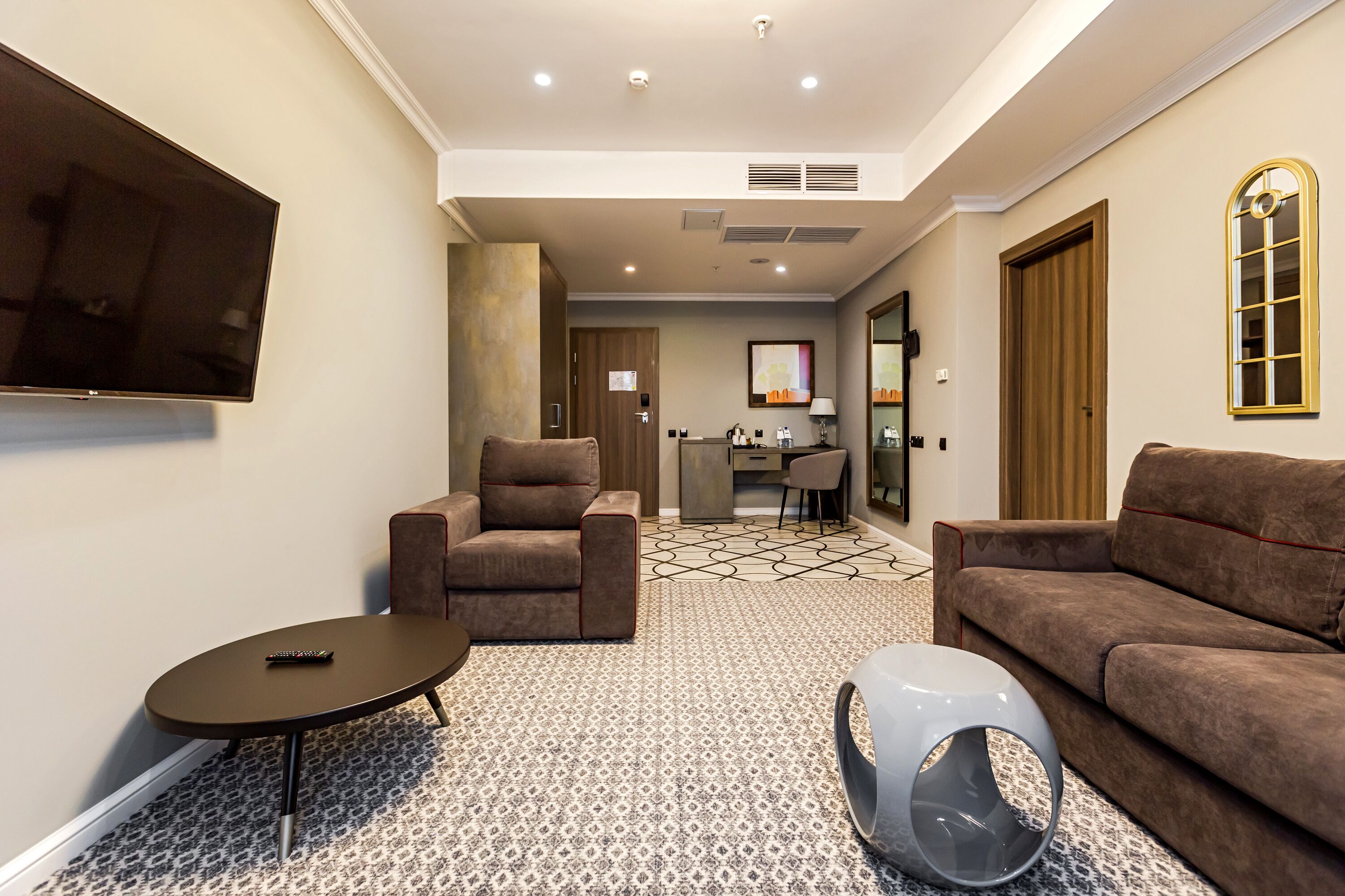 A modern living room with a sofa, armchair, and a unique pet bed.