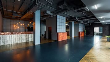Un'ampia hall con reception, ampie finestre e un pavimento misto di legno e tonalità scure.