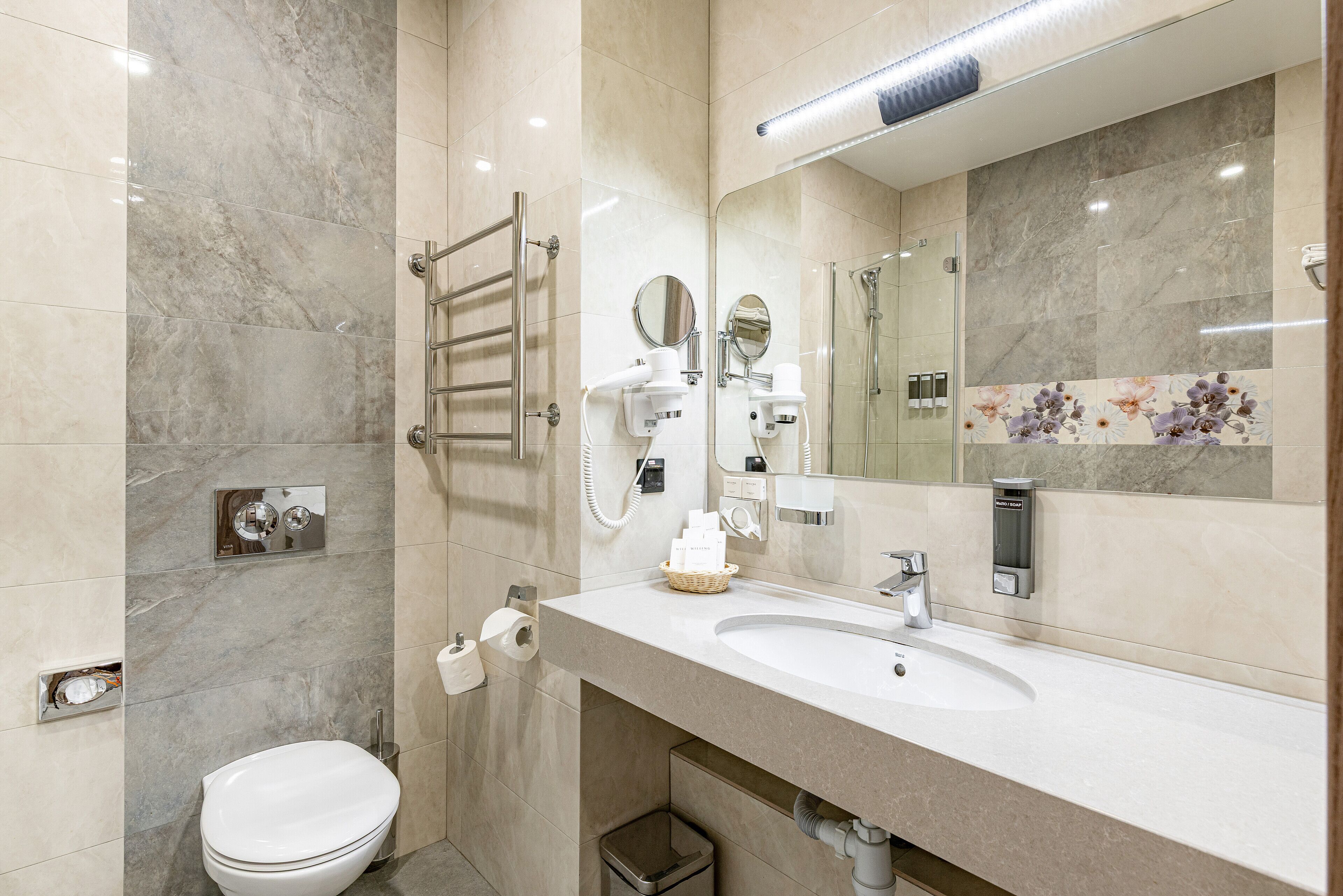 A modern bathroom with a white sink, a mirror, a towel rack, and a toilet.