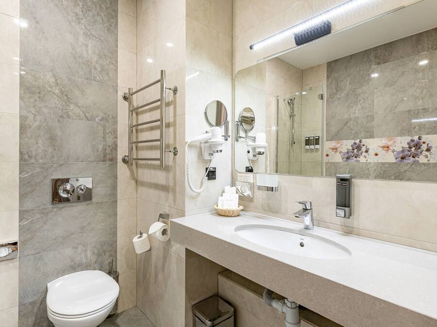 A modern bathroom with a white sink, a mirror, a towel rack, and a toilet.