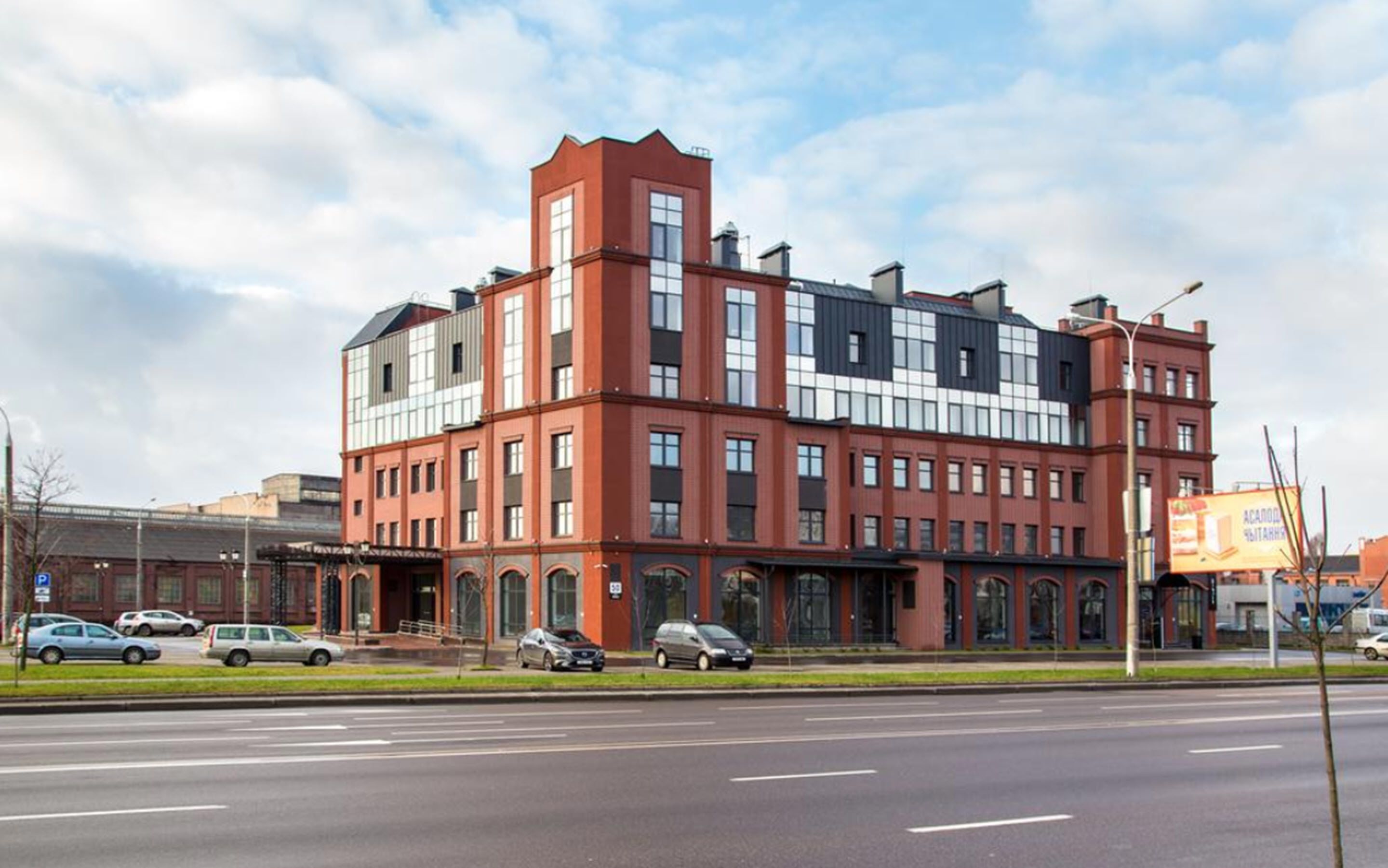 A multi-story building with a red brick facade, large windows, and a prominent corner entrance.
