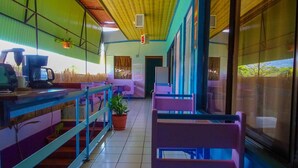 Un restaurant amb una barra llarga, cadires i plantes en testos.