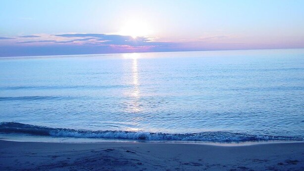 A beach with calm water and a clear sky.