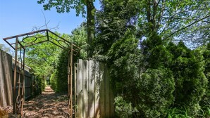 A wooden structure with a metal frame, surrounded by dense greenery and trees. - 1 bed/1 bath, 1.5 blocks to beach/town, dog friendly, fenced yard (Union Pier)