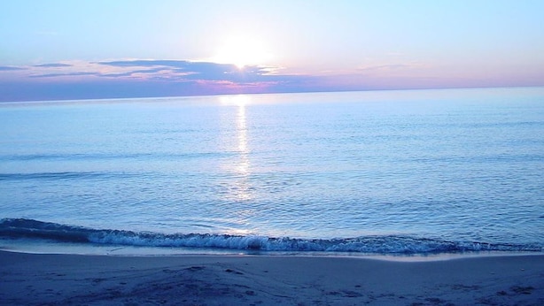 A beach with calm water and a clear sky. - 1 bed/1 bath, 1.5 blocks to beach/town, dog friendly, fenced yard (Union Pier)