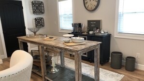 Uma área de refeições com uma mesa de madeira rústica, uma cadeira branca e uma porta preta.