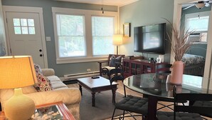 A living room with a sofa, coffee table, TV, and a dining area with chairs and a table.