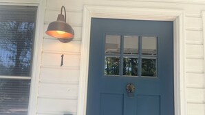 A blue door with a window, a mailbox, and a wall-mounted light fixture.