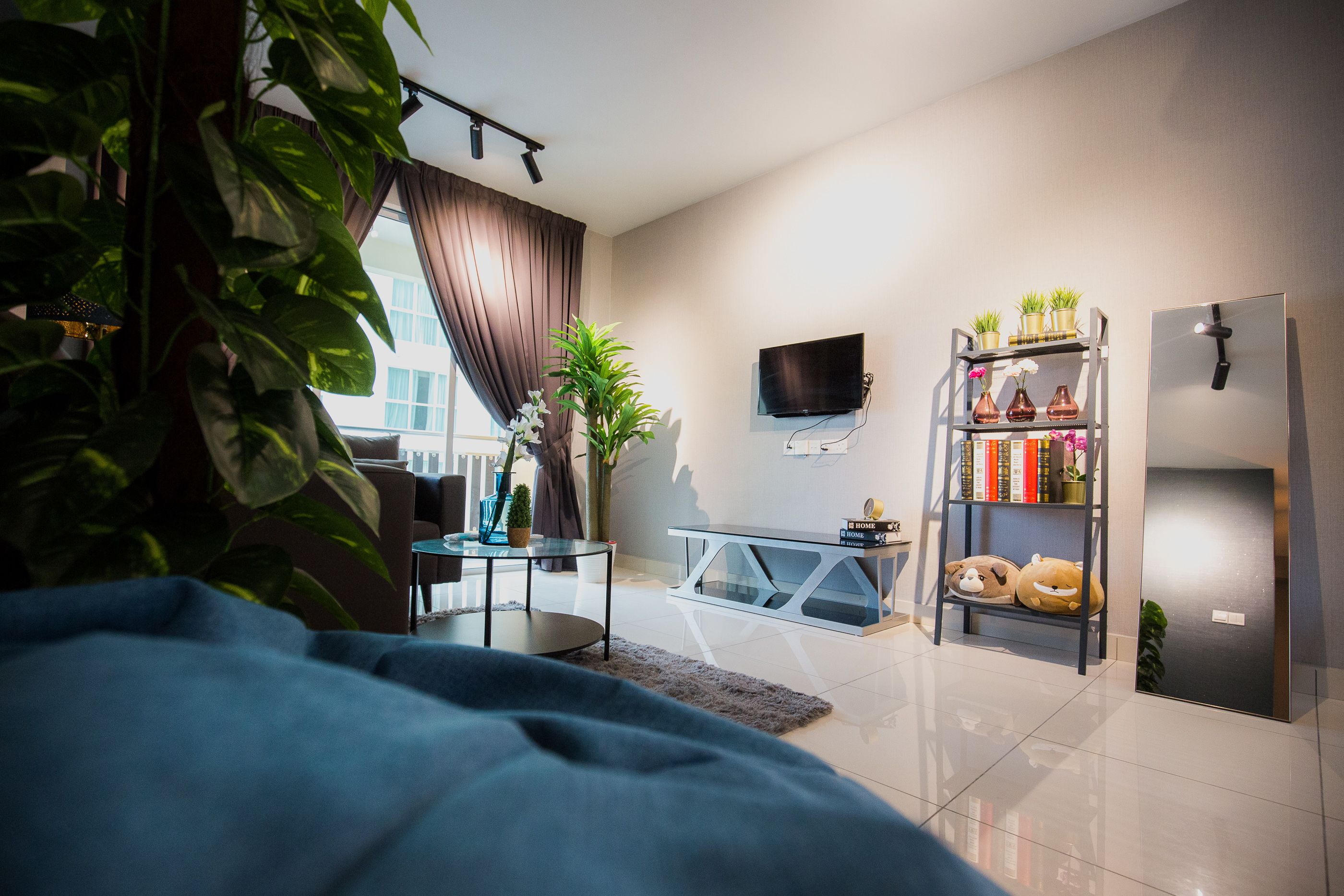 A modern living room with a sofa, a coffee table, a TV, a bookshelf, and a refrigerator.