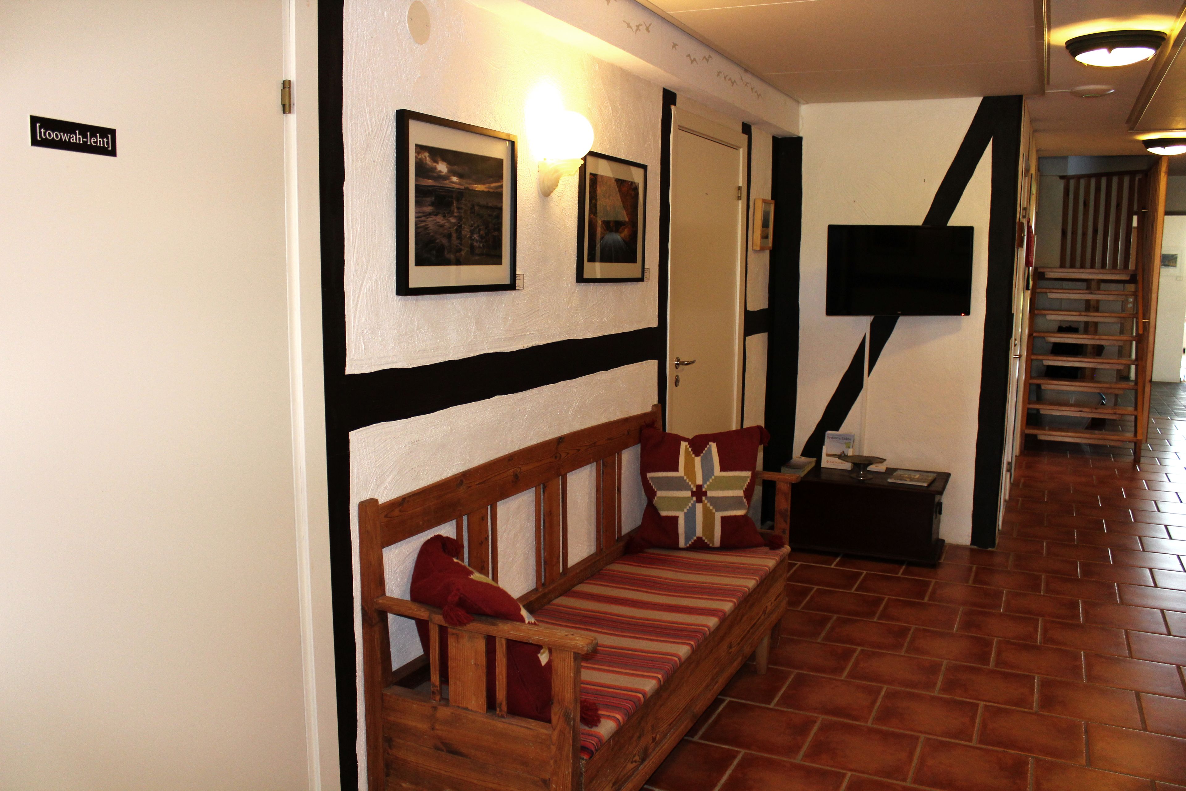 Ein Flur mit einer Holzbank, einem an der Wand befestigten Fernseher und einer Treppe.