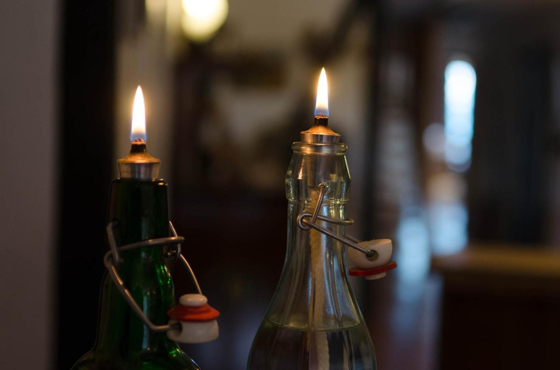Two glass bottles with metal clasps and a lit candle inside each.