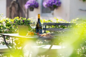 Una mesa con una botella de vino, copas y una cesta de flores.