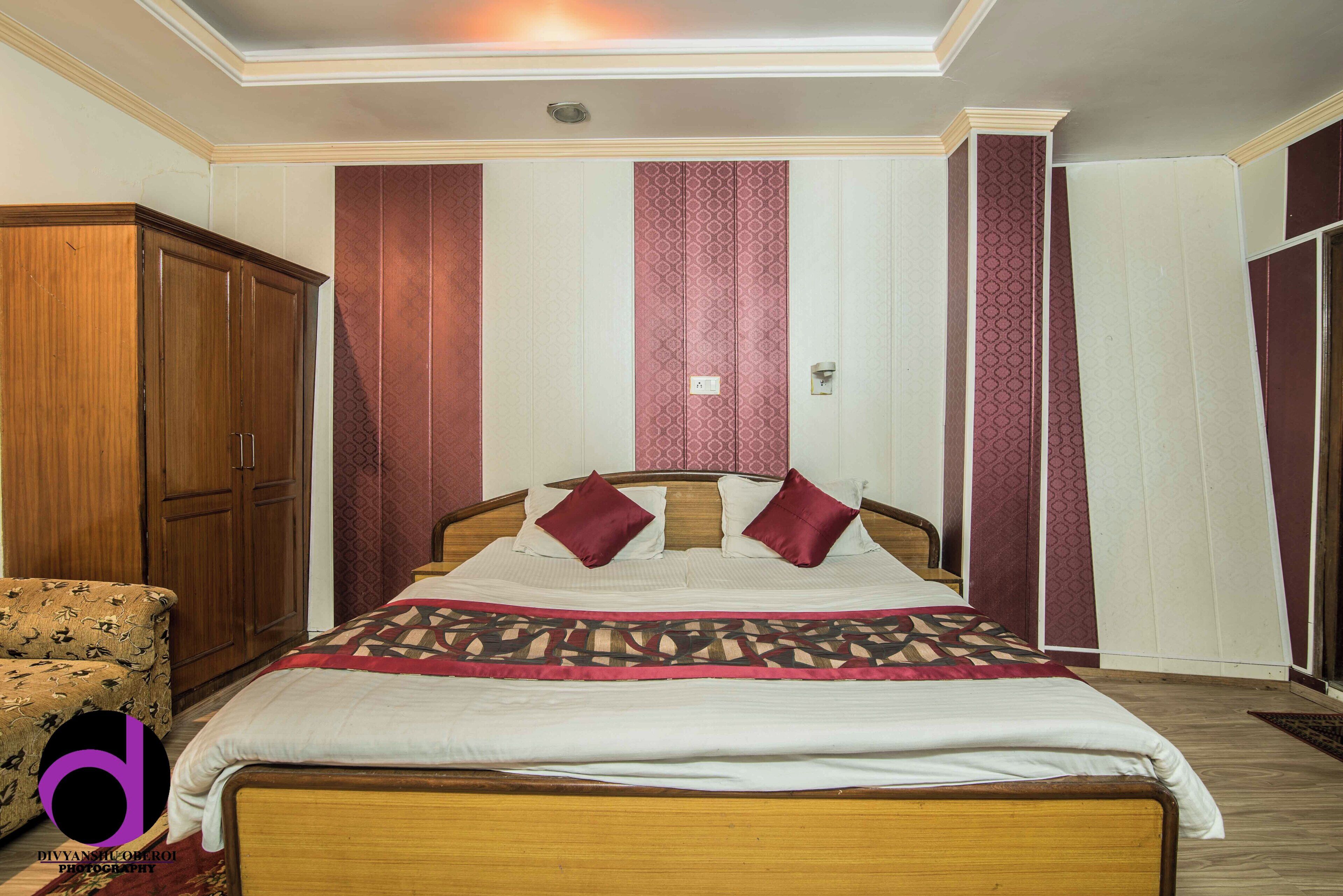 A bedroom with a bed, wooden wardrobe, and patterned walls.