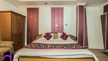 A bedroom with a bed, wooden wardrobe, and patterned walls.