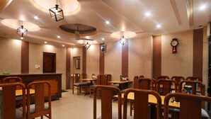 Un comedor con sillas y mesas de madera, una recepción y un reloj en la pared.